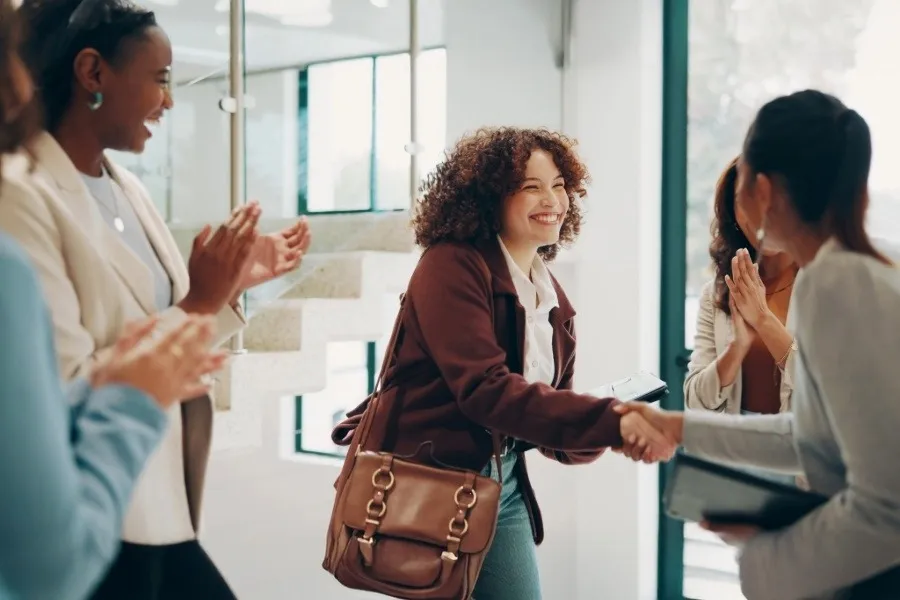 Woman in business suit shakes hands and receives applause