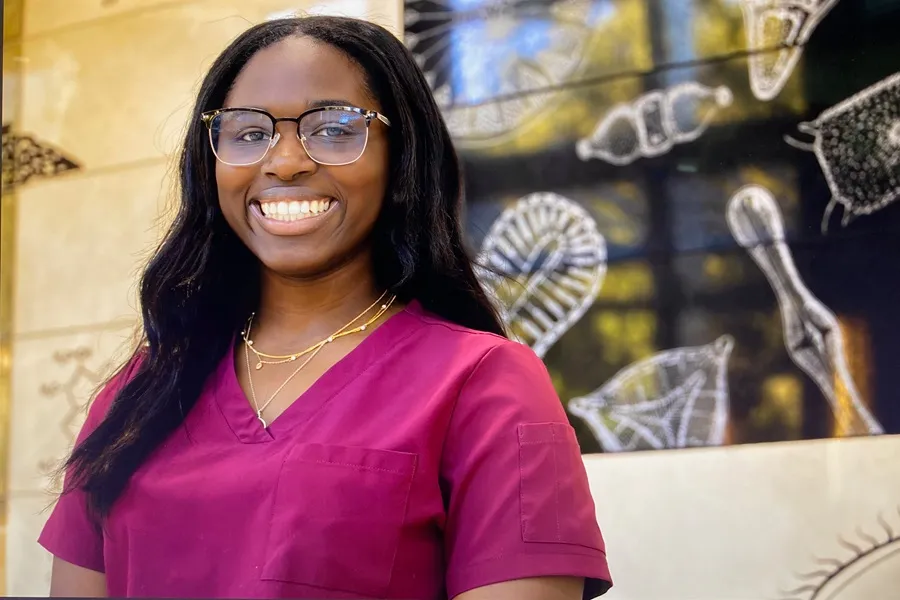 Student poses in front of decorated wall