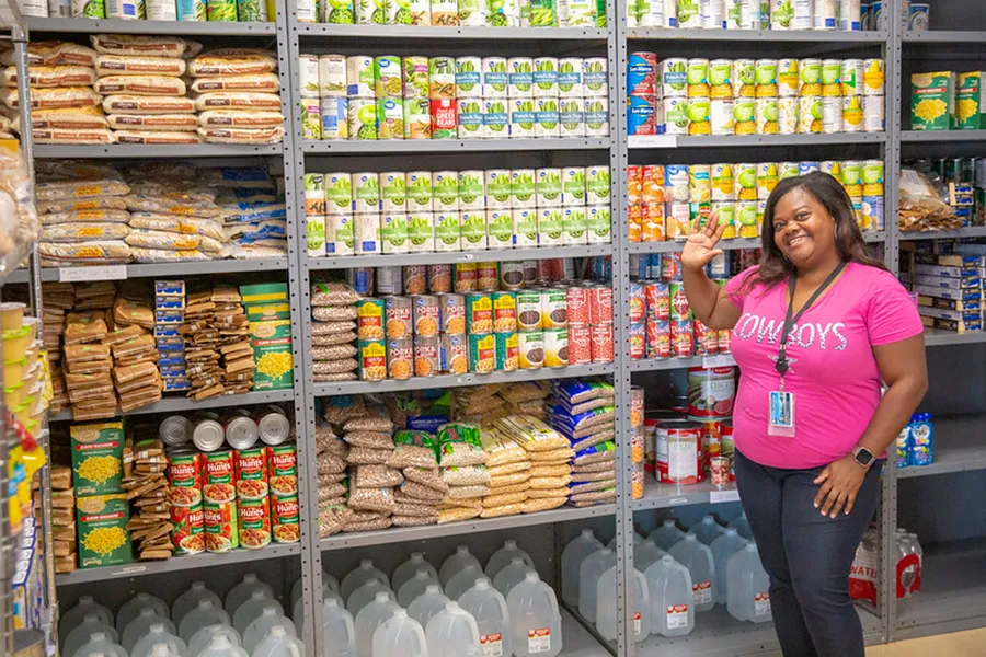 Volunteer standing in front of shelves of food.