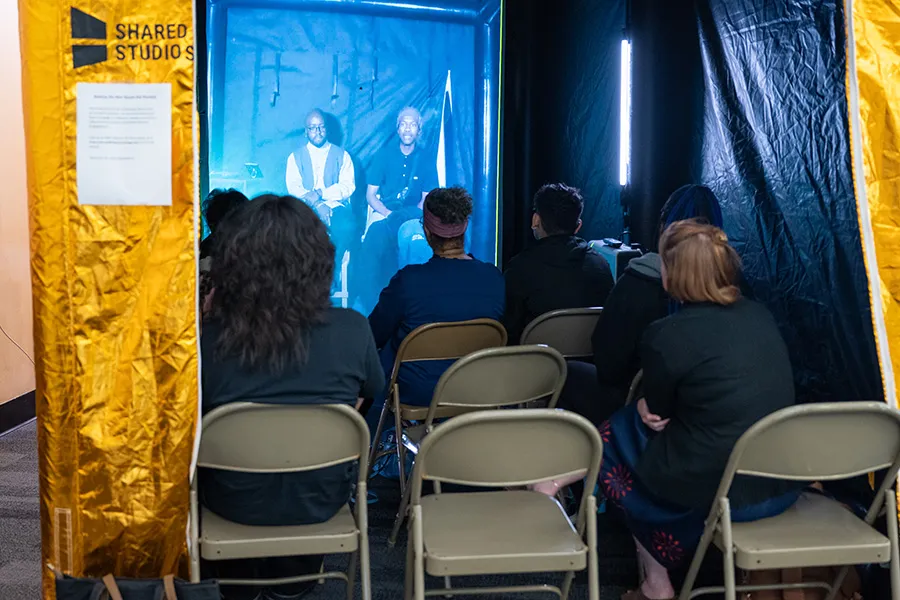 Students sit inside a portal tent facing a screen