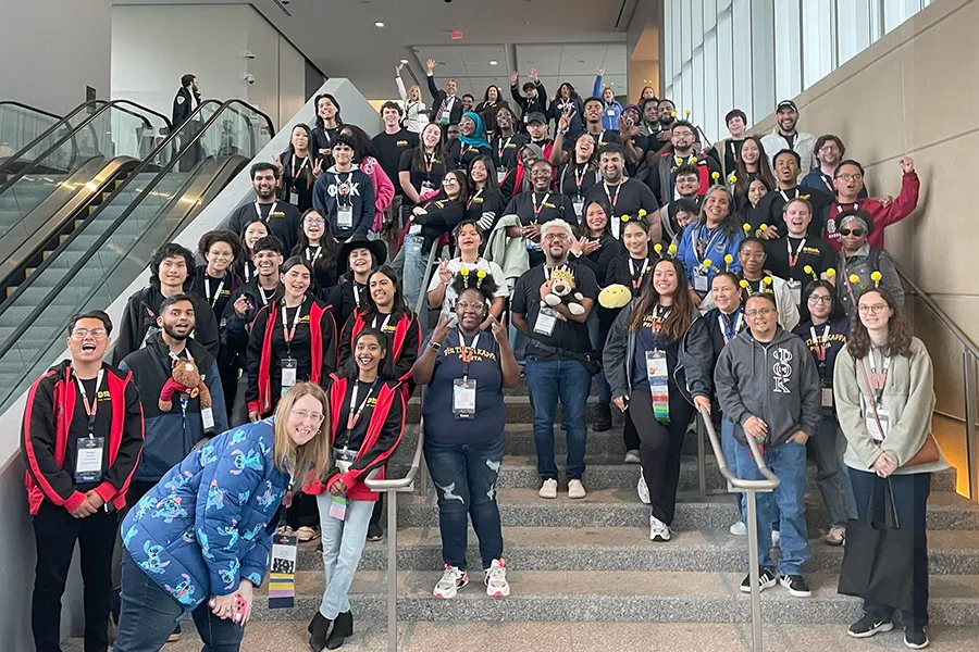 Students and advisors pose on stairs at event