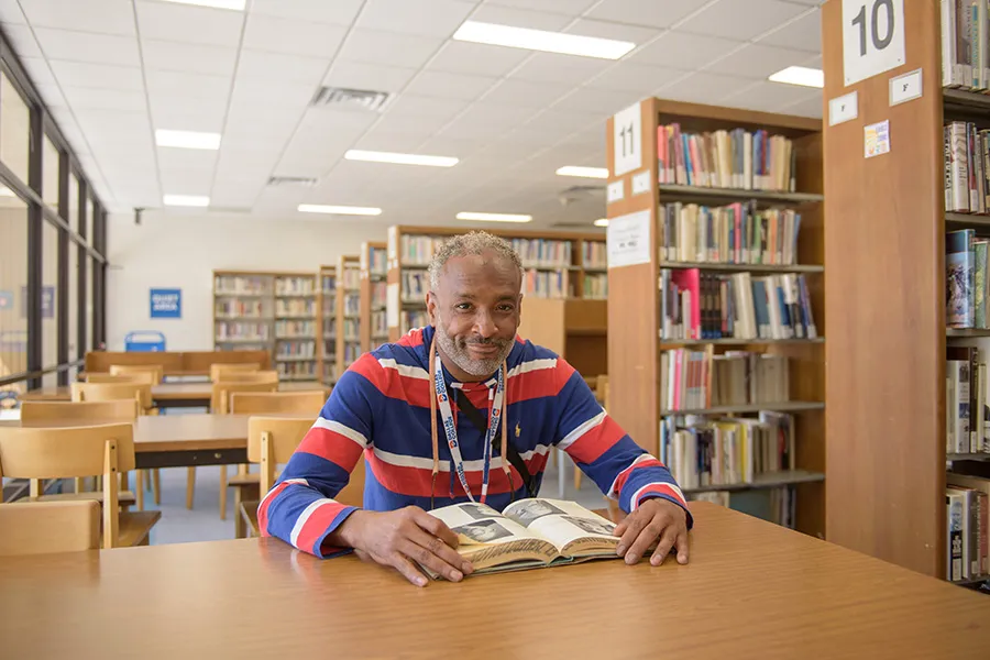 Rod Gordon sits at a table in the library, looking up from a book