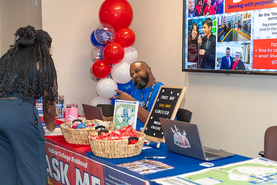 Dallas College employee offers student items during Welcome Week event.