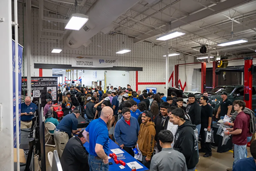 People walking through automotive expo at Dallas College Brookhaven automotive laboratory.