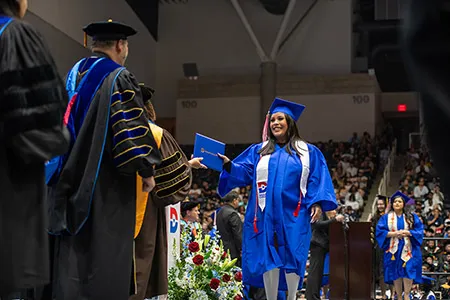 Dallas College graduate receives her diploma from the chancellor.