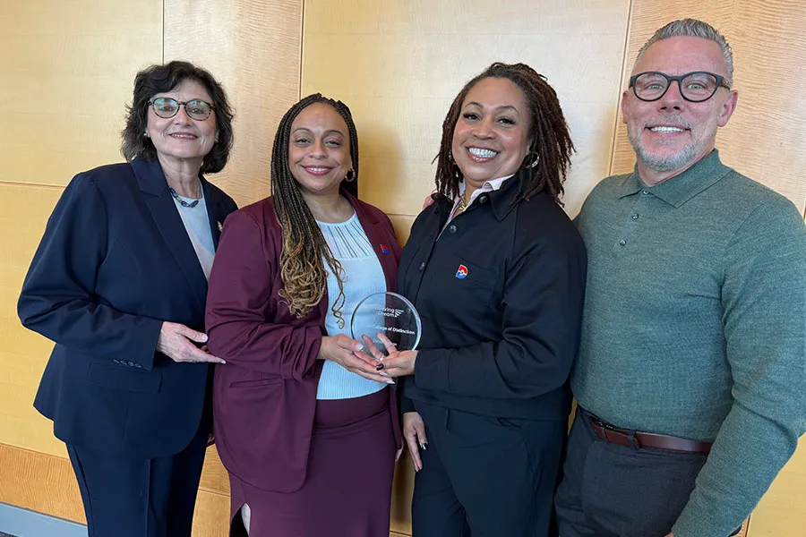 Four college administrators holding Achieving the Dream Leader College of Distinction award.