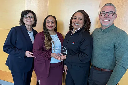 Four college administrators holding Achieving the Dream Leader College of Distinction award.