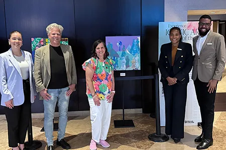 Amy Branch-Lambert stands with her painting next to staff from the Omni hotel.