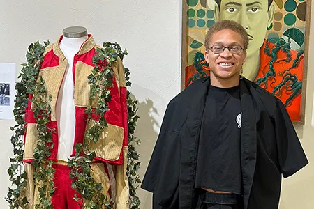 Christian Henderson standing next to a garment he designed.