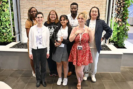 Group of seven students posing with a TIPA trophy.