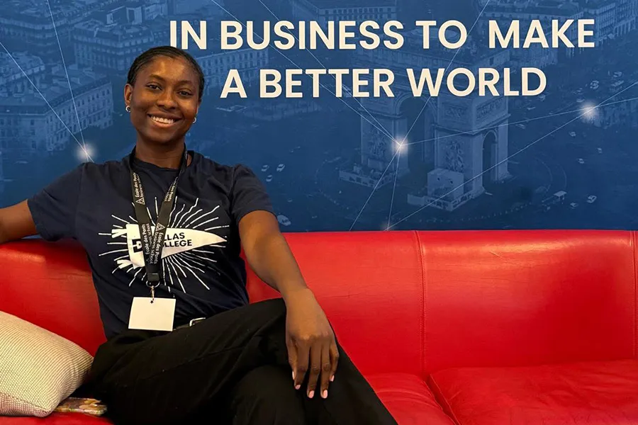 Emmanuella Iwuji sitting on sofa in front of wall that reads: 