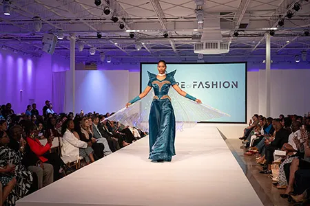 Model in blue gown walks the runway in fashion show.