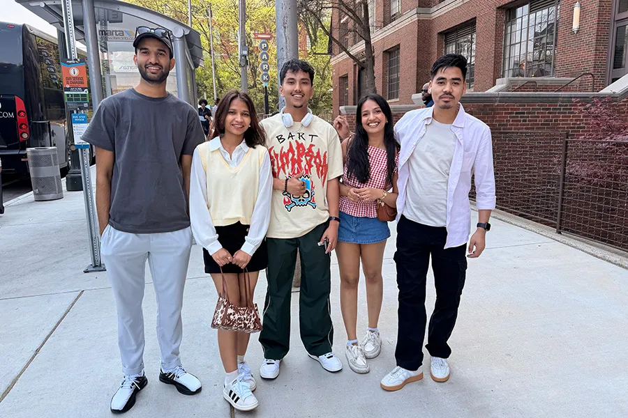 Five students are pictured together on a city sidewalk.