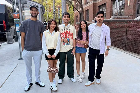 Five students are pictured together on a city sidewalk.