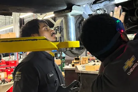 Two people working underneath a car.