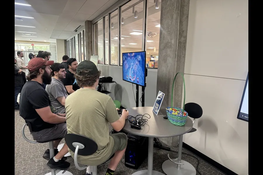 Students sitting around a screen playing video games