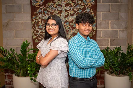 Two Dallas College interns are pictured standing back to back with arms crossed.