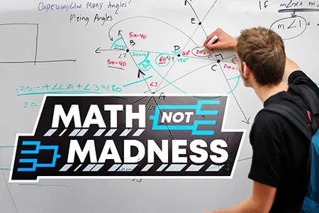 A student writes math equations on a dry erase board.