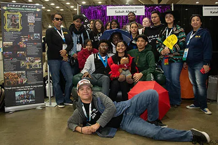 Group of students gathered in front of a booth at PTK Catalyst.