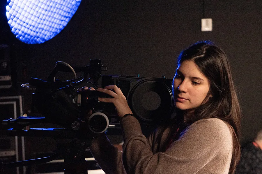 Rebekah Gonzalez stands behind a camera.