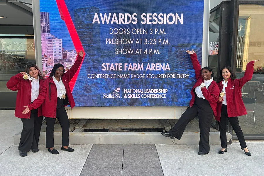 Four students pointing to a screen that reads: Awards Session, Doors Open 3 p.m., Preshow at 3:25 p.m., Show at 4 p.m., State Farm Arena, National Leadership & Skills Conference