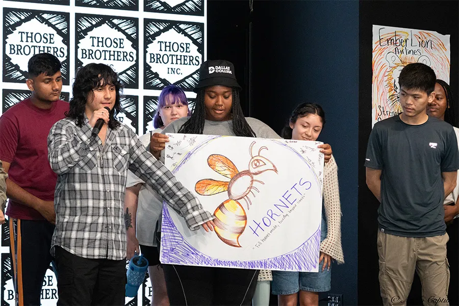 Seven Dallas College students stand on stage and present a drawing they made in one of the Summer Student Leadership Retreat sessions.