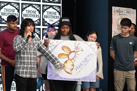 Seven Dallas College students stand on stage and present a drawing they made in one of the Summer Student Leadership Retreat sessions.