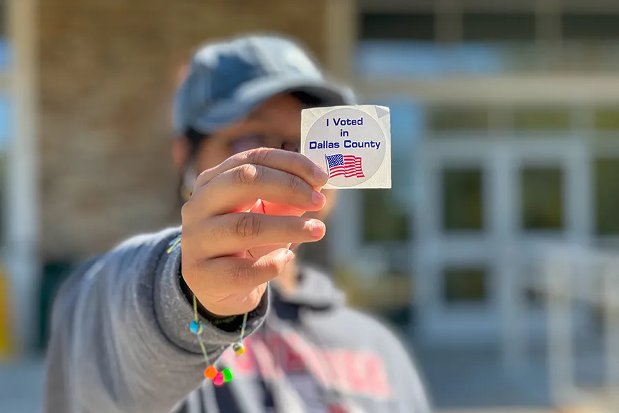 A student holds up a sticker that says 