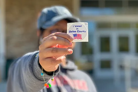 A student holds up a sticker that says 