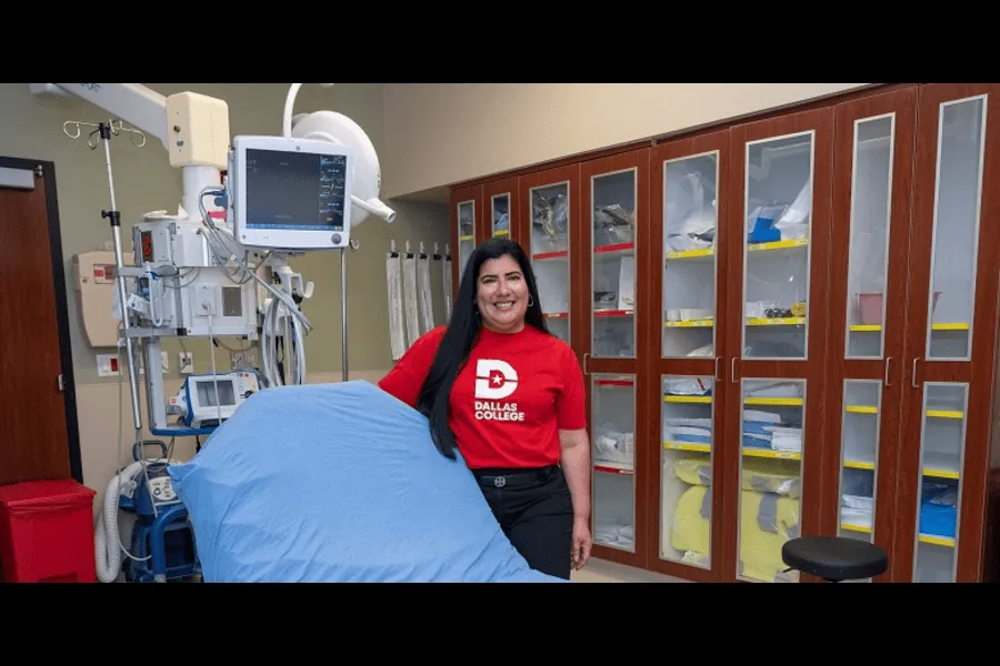 Woman in red dallas college shirt next to medical bed