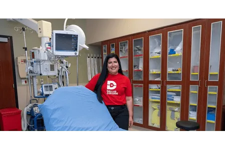Woman in red dallas college shirt next to medical bed