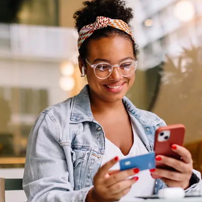 Student holding phone and credit card making a payment