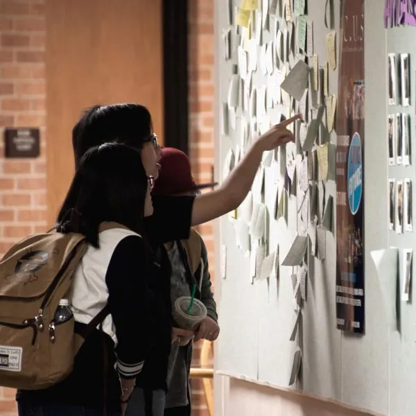 Students at a Dallas College bulletin board looking for inormation