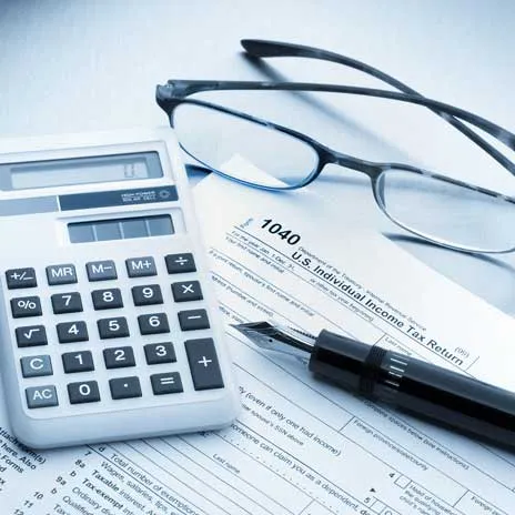 1040 tax form with calculator, glasses, and pen.