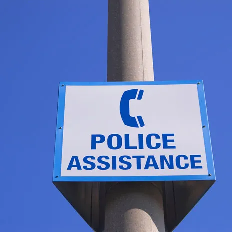 Sign reading 'POLICE ASSISTANCE' with a telephone icon, mounted on a pole