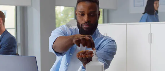 A person uses a hand sanitizer pump