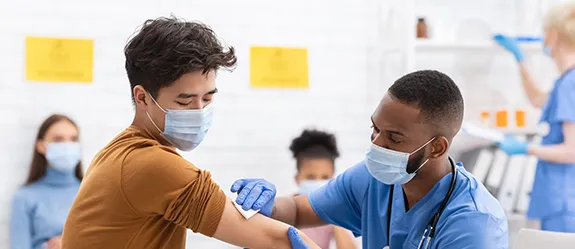 A health care worker rubs an alcohol swab on a man's arm in preparation for giving a shot
