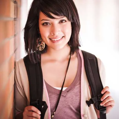 Student with a backpack standing against a brick wall, representing a welcoming and supportive environment for disability services