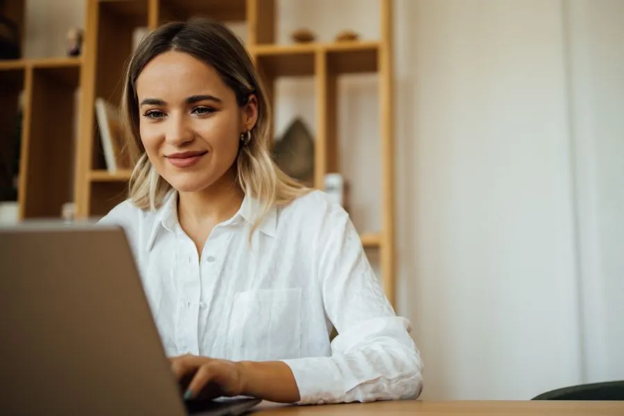 A woman sits at a desk and works on her laptop