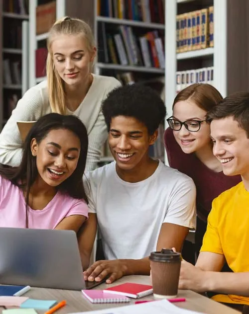 Group of students around a laptop in a library