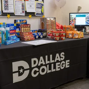 Table with food and household items at Dallas College Pack the Pantry event.
