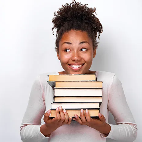Student smiling while holding a stack of books
