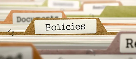 Close-up of file folders with a focus on a tab labeled 'Policies'.