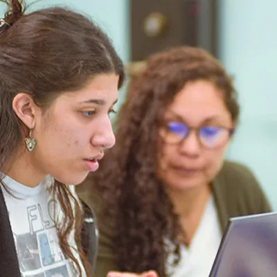 A student and a teacher look over information on a laptop screen