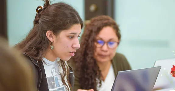 A student and a teacher look over information on a laptop screen