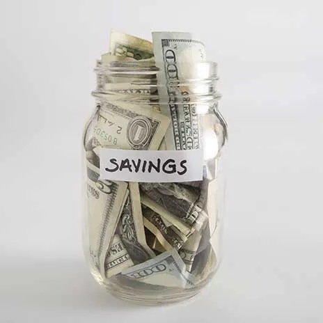 Glass jar labeled 'Savings' filled with U.S. dollar bills, representing financial savings and budgetin