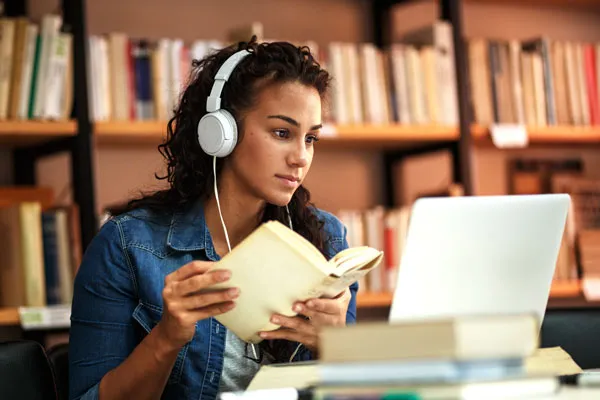 Student studying in a library with headphones on