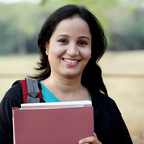 student holding her class materials smiling