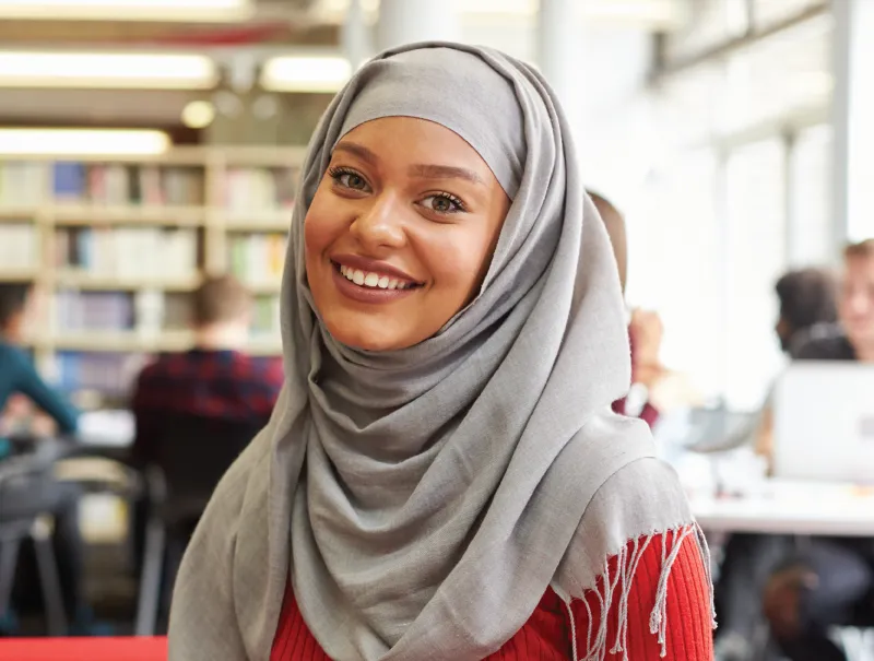 a portrait of a student smiling inside of college library