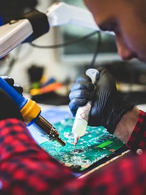 A worker soldering a mother board